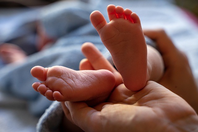 Bild vergrößern: Das Bild zeigt ein paar Babyfüße auf einer Hand.