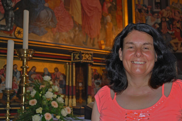 Bild vergrößern: Eine Frau steht in der Kirche vor dem Altar.